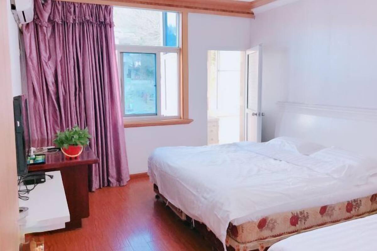Une chambre d’hôtel avec un lit, un bureau équipé d’un ordinateur, une fenêtre avec des rideaux et une vue sur l’extérieur.
