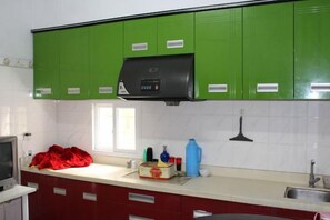A kitchen with green cabinets, a black range hood, a window, and a red countertop. - Zhoushan Tahua Xiaozhuang Impression Hotel (Zhoushan)