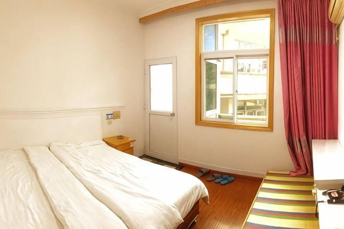 Une chambre à coucher avec un lit, une fenêtre, une porte et un tapis à rayures.