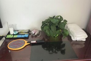 A desk with a laptop, a tennis racket, a plant, and a neatly folded towel. - Zhoushan Tahua Xiaozhuang Impression Hotel (Zhoushan)