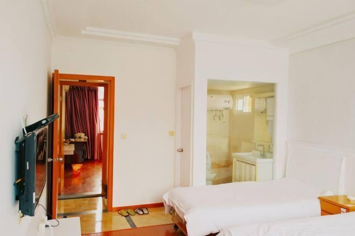 Une chambre d’hôtel avec un lit, une télévision, un bureau et une salle de bain, visibles à travers une porte ouverte.