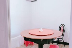 A round table with a red top and a white object on it, a black metal chair with a floral pattern, and a white wall in the background. - Zhoushan Tahua Xiaozhuang Impression Hotel (Zhoushan)