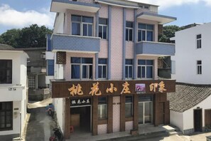 A multi-story building with a sign indicating a hotel. - Zhoushan Tahua Xiaozhuang Impression Hotel (Zhoushan)
