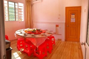 A round table with a white tablecloth and red chairs, a window with curtains, and a door with a sign. - Zhoushan Tahua Xiaozhuang Impression Hotel (Zhoushan)