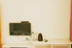 A TV mounted on a white wall with a small shelf below it. - Zhoushan Tahua Xiaozhuang Impression Hotel (Zhoushan)