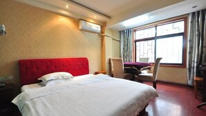 Habitación de hotel con una cama grande, cabecera roja, escritorio y una silla.