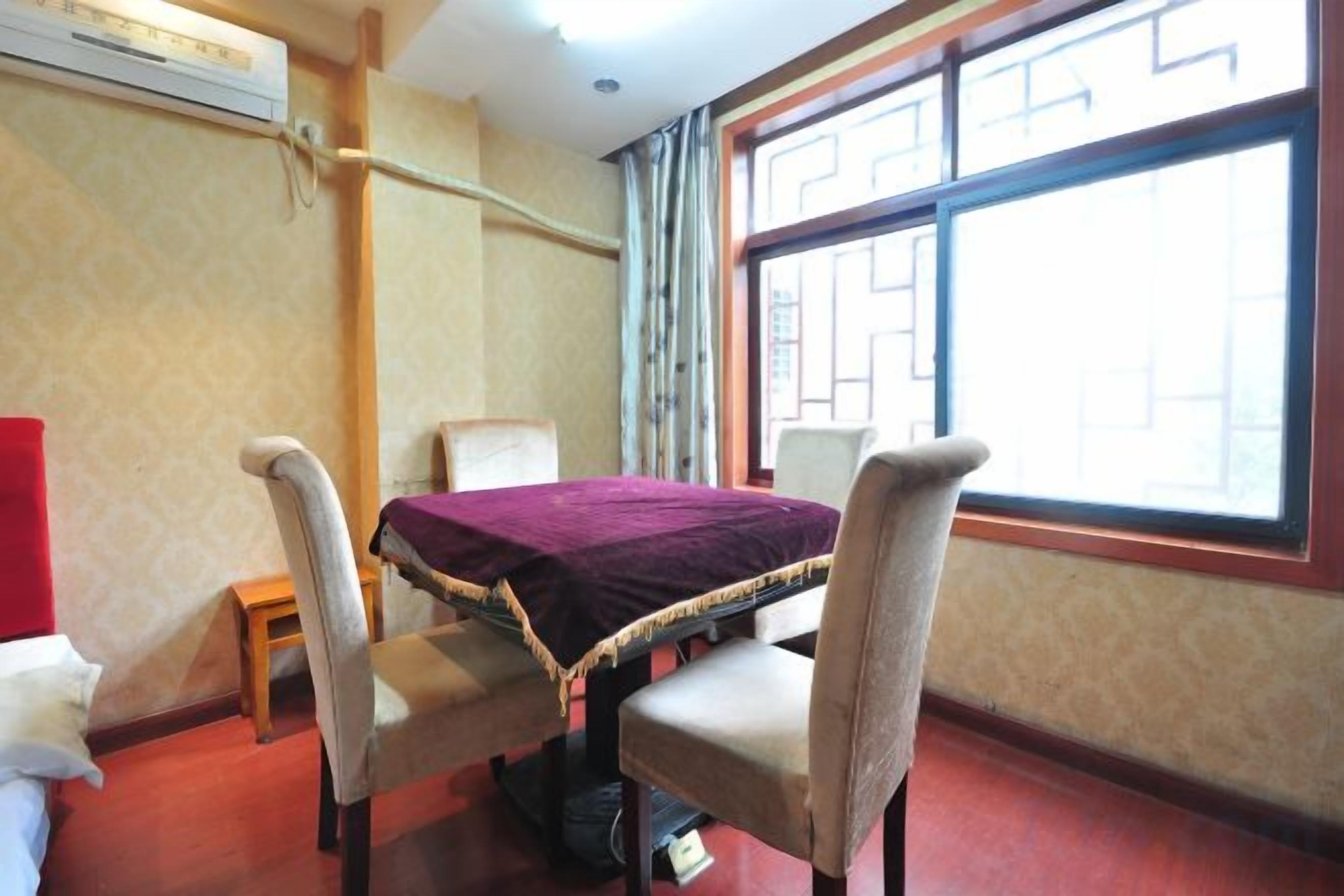 A room with a dining table, two chairs, a small stool, and a window with a view.