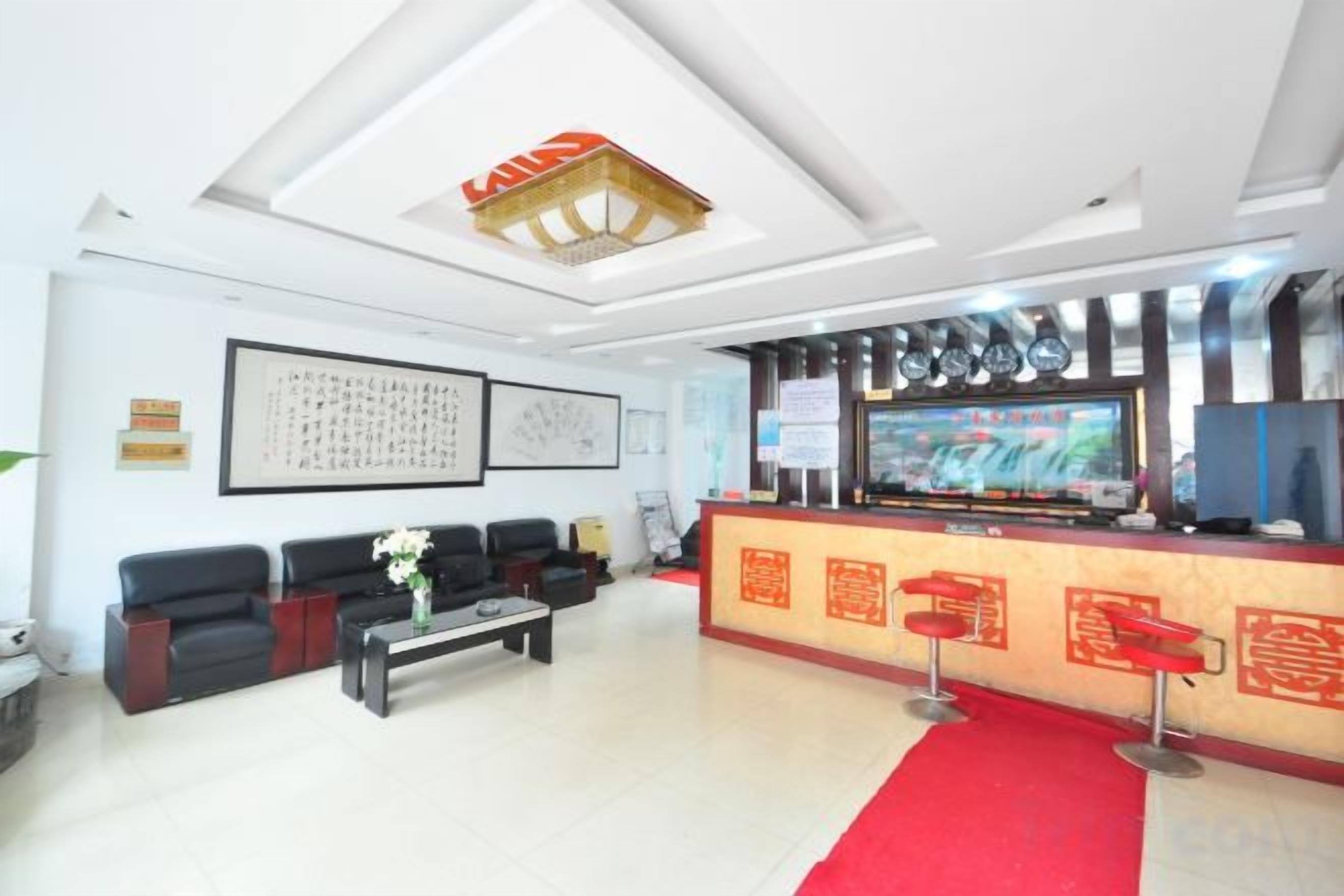 A hotel lobby with a reception desk, seating area, and a red carpet.