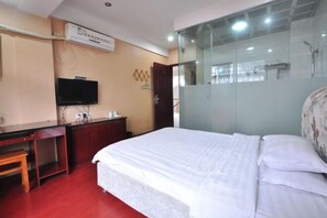 A hotel room with a bed, a desk, a television, and a glass partition. - Chaohu Jiangnan Hotel (Chaohu)