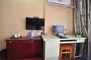 A room with a desk, a television, a computer, and a small cabinet. - Chaohu Jiangnan Hotel (Chaohu)