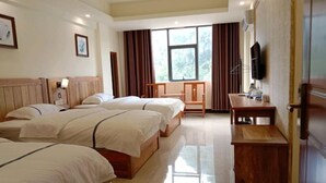 A hotel room with three beds, a desk, a TV, and a window with curtains. - Green Island Hotel (Daxin)