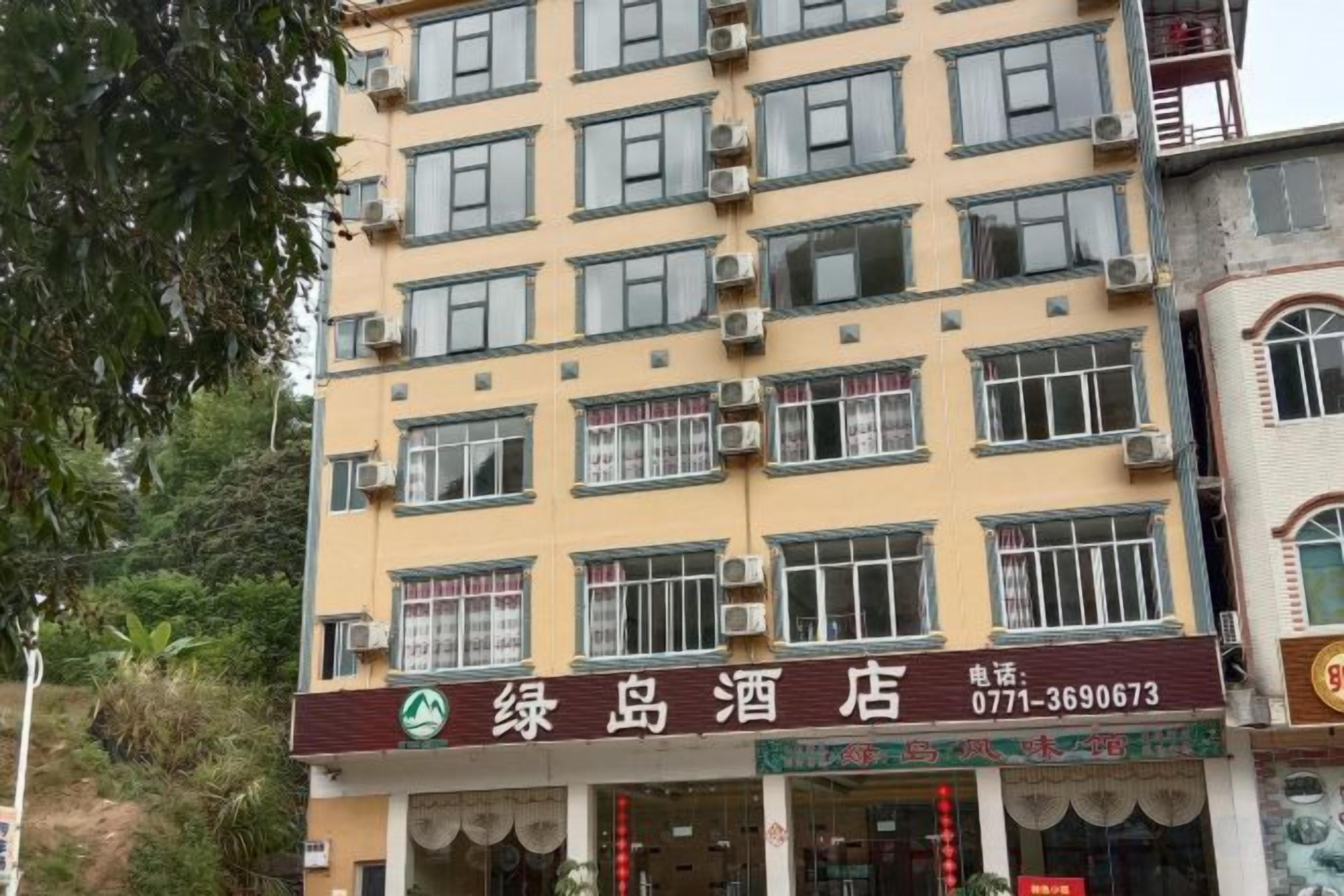 A multi-story hotel with a signboard displaying the name and contact number.