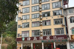 A multi-story hotel with a signboard displaying the name and contact number. - Green Island Hotel (Daxin)