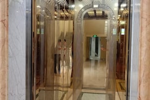 Un ascensor con piso de mármol y puerta de vidrio.