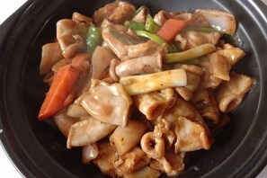 A stir-fried dish with vegetables and meat in a black bowl. - Green Island Hotel (Daxin)