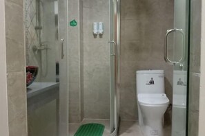 A bathroom with a glass shower enclosure, a toilet, and a sink. - Green Island Hotel (Daxin)