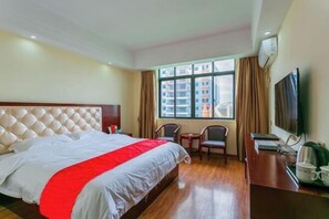 A hotel room with a large bed, a TV, a coffee maker, and a window with curtains. - Hande Hotel (Baise)