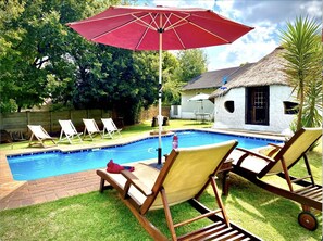 Relax by the pool surrounded by a lush lawn and shaded lounge chairs.