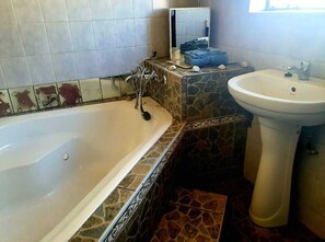 Bathroom features a large bathtub and pedestal sink with a mirror above.