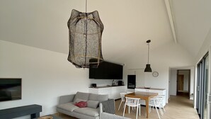 Una sala de estar moderna con un sofá gris, una mesa de centro y un comedor con una mesa de madera y sillas.