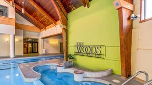 Sisätiloissa sijaitseva uima-allas, jonka yhteydessä on kyltti, jossa lukee: ”The Woods Resort and Spa”.