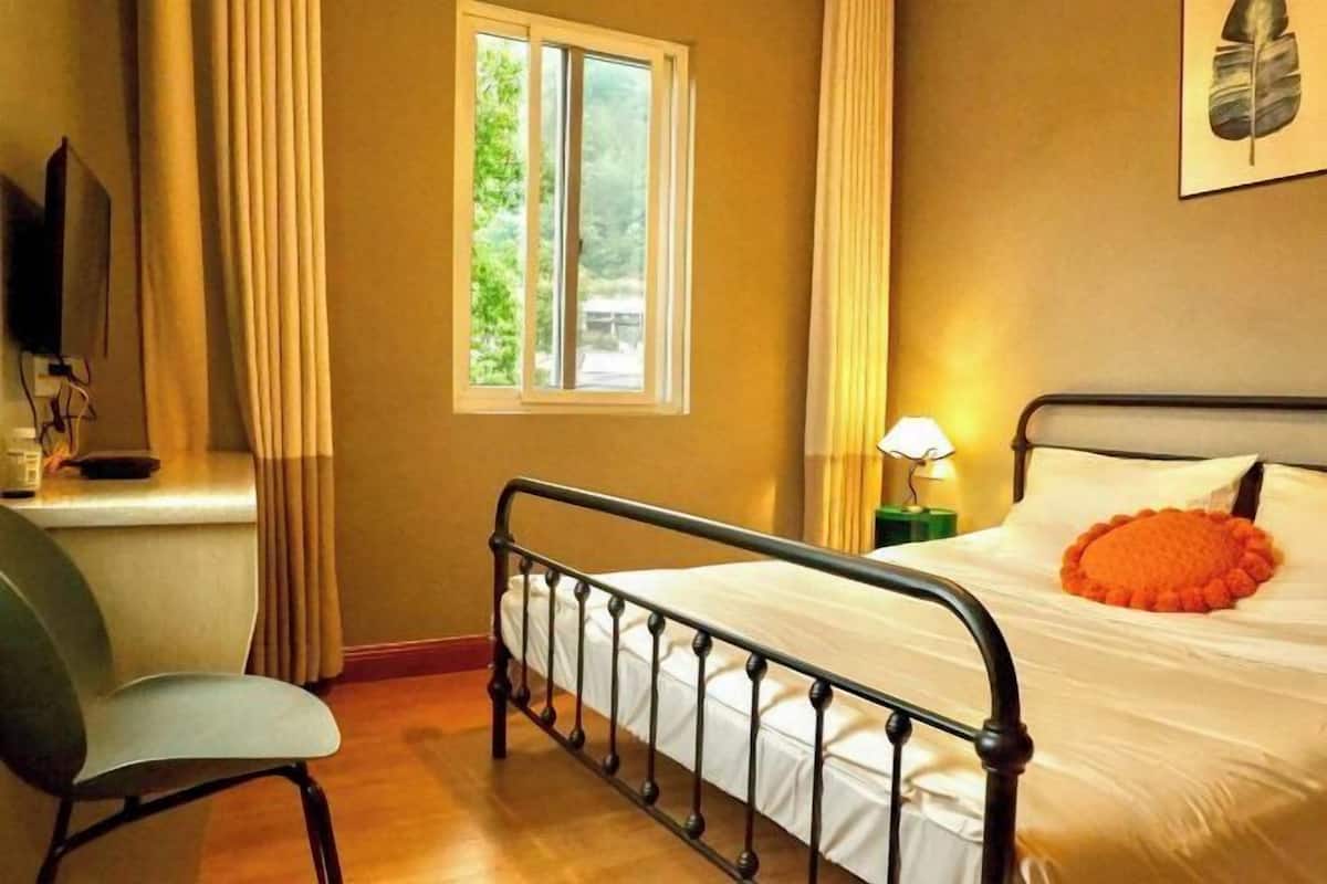A bedroom with a bed, a chair, a desk, a lamp, and a window.