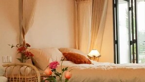 A hotel room with a bed, a chair, a table with a vase of flowers, and a window with curtains. - Shanerqi Homestay in Xinchang (Xinchang)