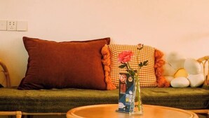 A room with a sofa, a round coffee table, and a vase with flowers. - Shanerqi Homestay in Xinchang (Xinchang)