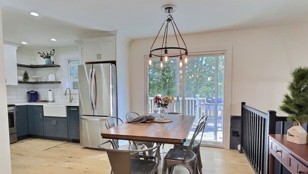 A modern kitchen with a wooden dining table, metal chairs, and a hanging light fixture.