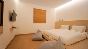 Ein Schlafzimmer mit einem Bett, einem an der Wand montierten Fernseher, einem Fenster mit Jalousien und Holzboden.
