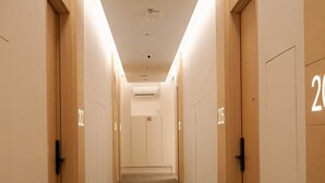 A hotel corridor with carpeted floors, wooden doors, and numbered room signs. - Manuka By Havis Hotel at Penuin (Batam)