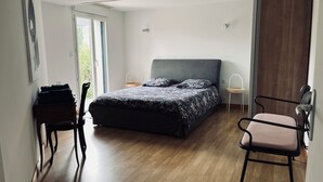 A bedroom with a bed, a chair, a desk, and a window.