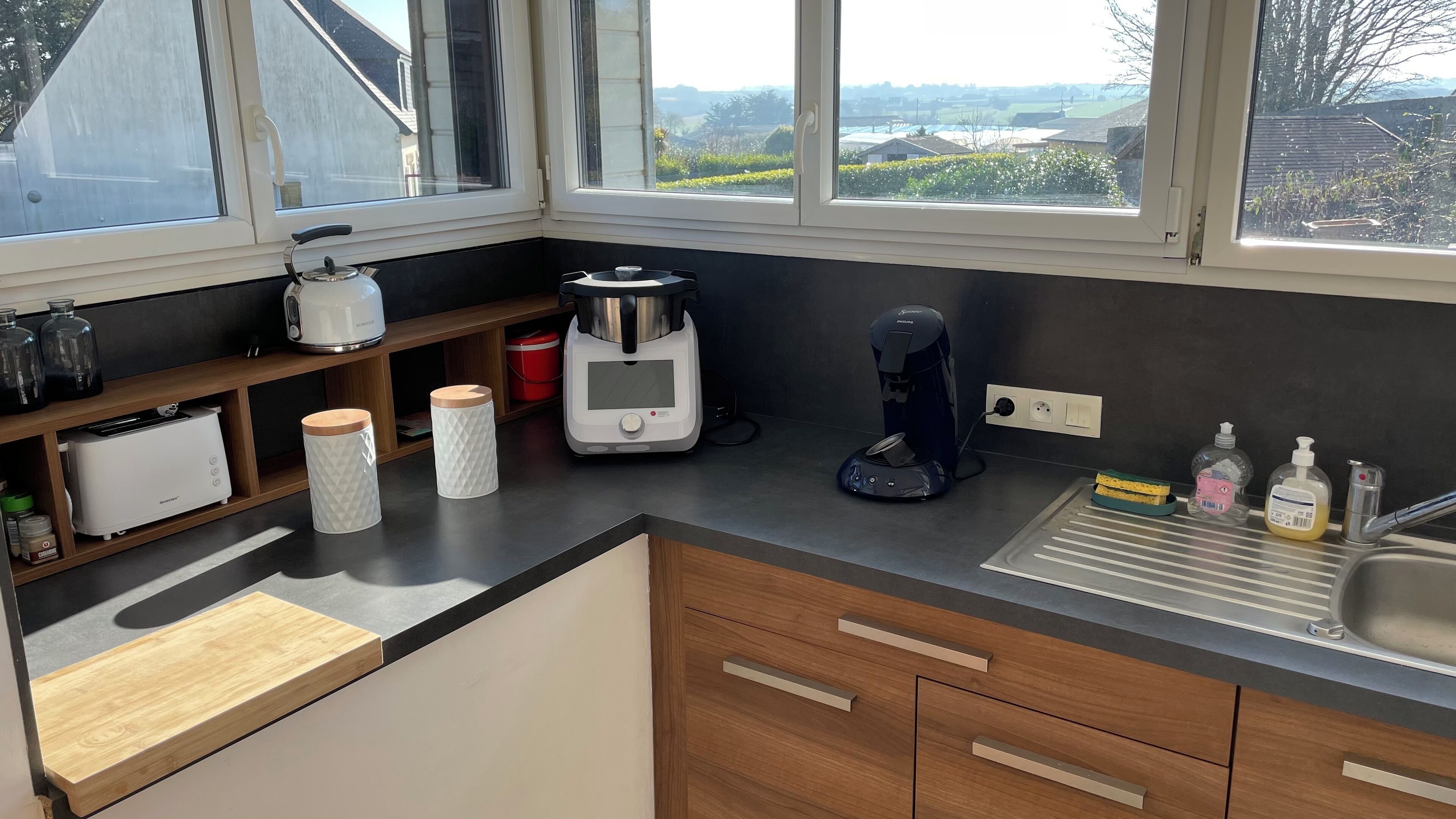 Une cuisine moderne dotée d’une grande fenêtre, d’une machine à café, d’un grille-pain et d’une bouilloire.