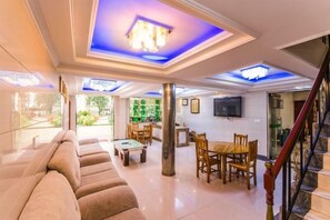 A spacious living area with a sofa, dining table, and chairs, a staircase, and a TV mounted on the wall. - Mingxiuya Leisure Villa (Emeishan City)
