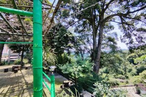 A green metal structure, possibly a part of a garden or park, with a pathway leading through a lush, green area with trees and plants. - Mingxiuya Leisure Villa (Emeishan City)