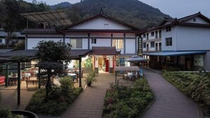 A traditional building with a tiled roof, a covered entrance, and a pathway leading to a seating area. - Mingxiuya Leisure Villa (Emeishan City)