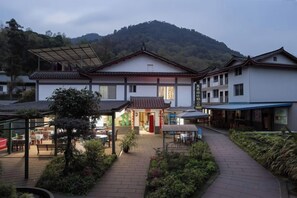 A traditional building with a central entrance, a covered outdoor seating area, and a pathway leading to the entrance. - Mingxiuya Leisure Villa (Emeishan City)