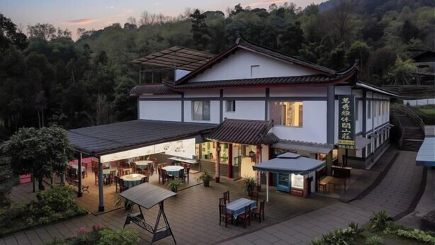 A traditional building with a covered patio area, a dining section, and a sign with Chinese characters. - Mingxiuya Leisure Villa (Emeishan City)
