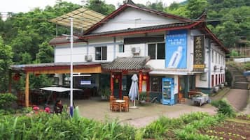 A traditional building with a tiled roof, a covered outdoor seating area, and a signboard.