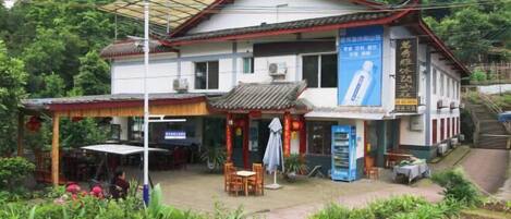 A traditional building with a tiled roof, a covered outdoor seating area, and a signboard.