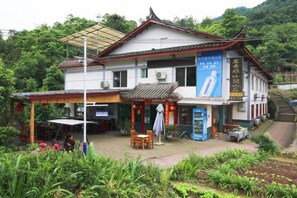 A traditional building with a tiled roof, a covered outdoor seating area, and a signboard. - Mingxiuya Leisure Villa (Emeishan City)