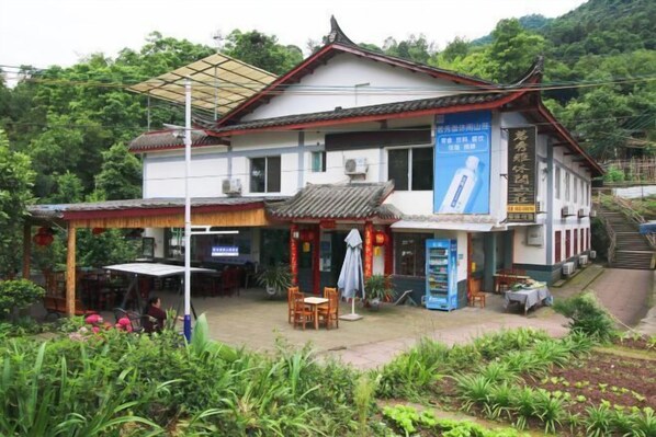 A traditional building with a tiled roof, a covered outdoor seating area, and a signboard. - Mingxiuya Leisure Villa (Emeishan City)