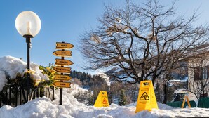 A snow-covered street with directional signs for various cities and a caution wet floor sign.