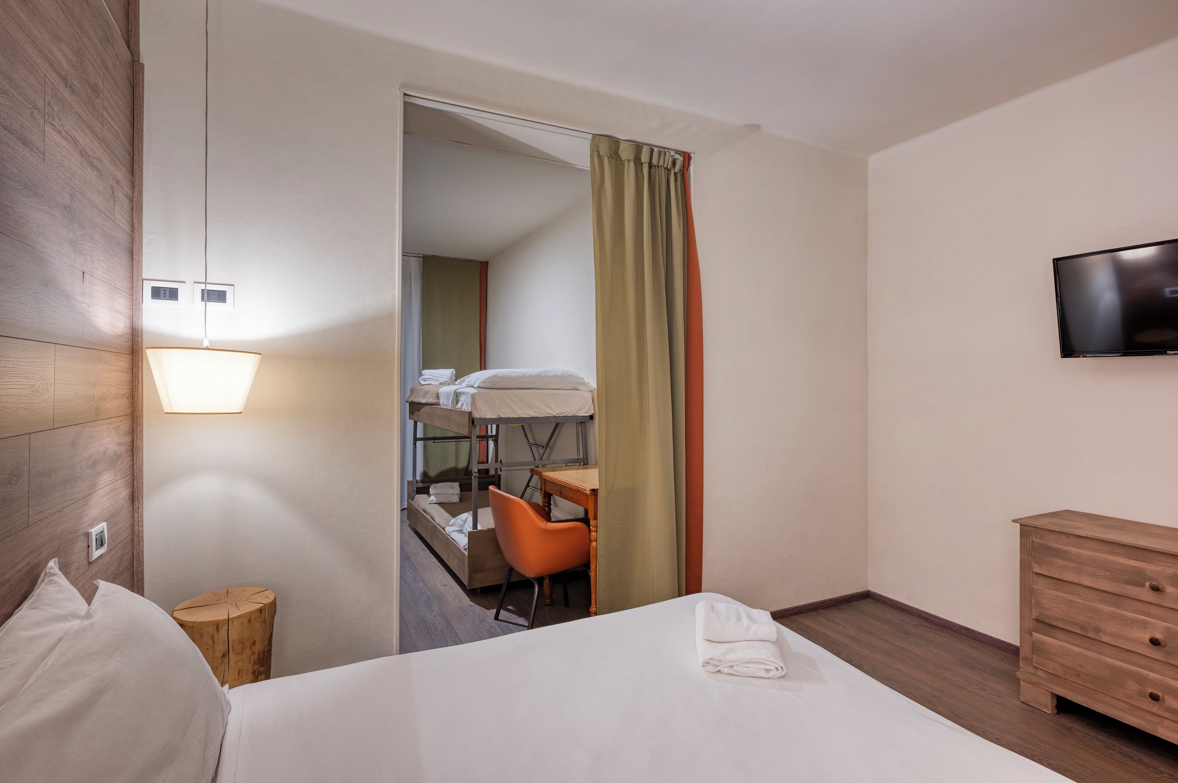 Une chambre d’hôtel comprenant un lit, un bureau, une chaise, un téléviseur et une commode en bois.