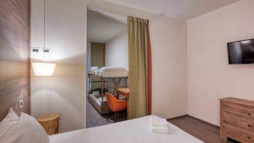 Une chambre d’hôtel comprenant un lit, un bureau, une chaise, un téléviseur et une commode en bois.