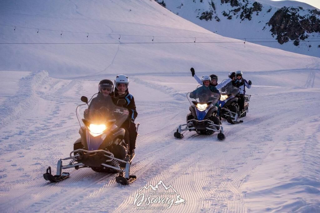 A group of people on snowmobiles on a snowy slope.
