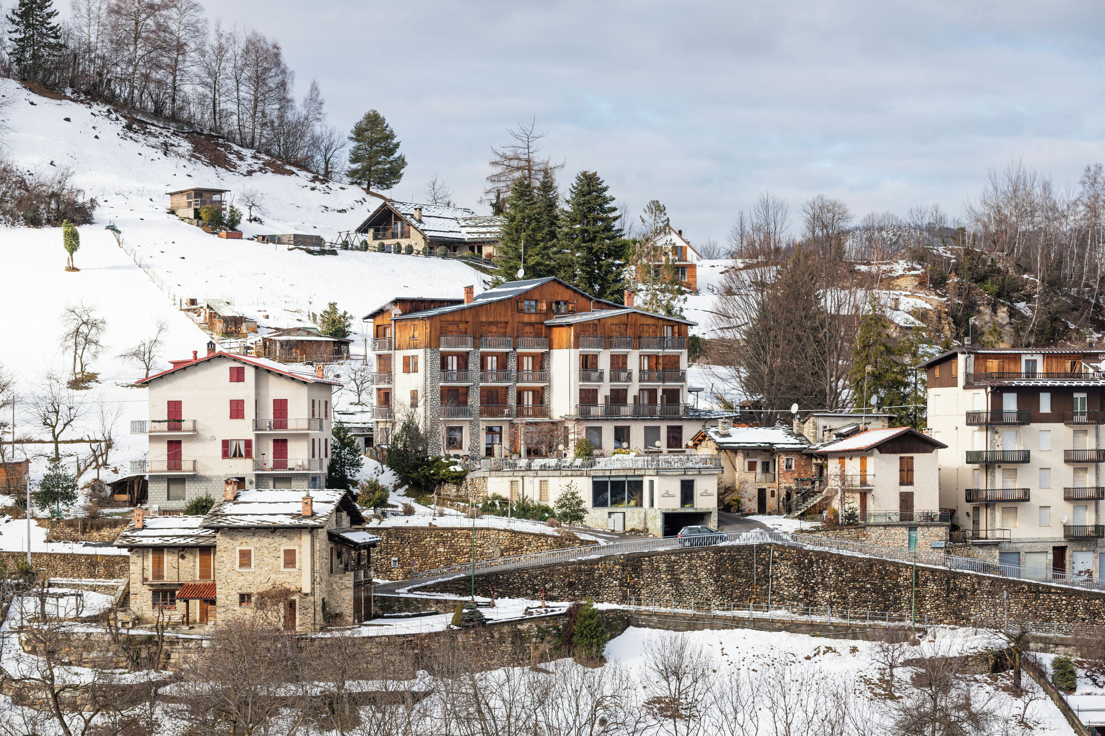 Une ville de montagne enneigée, avec des immeubles à plusieurs étages, dont un hôtel imposant doté de balcons et d’une façade en pierre.