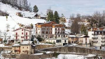 Une ville de montagne enneigée, avec des immeubles à plusieurs étages, dont un hôtel imposant doté de balcons et d’une façade en pierre.