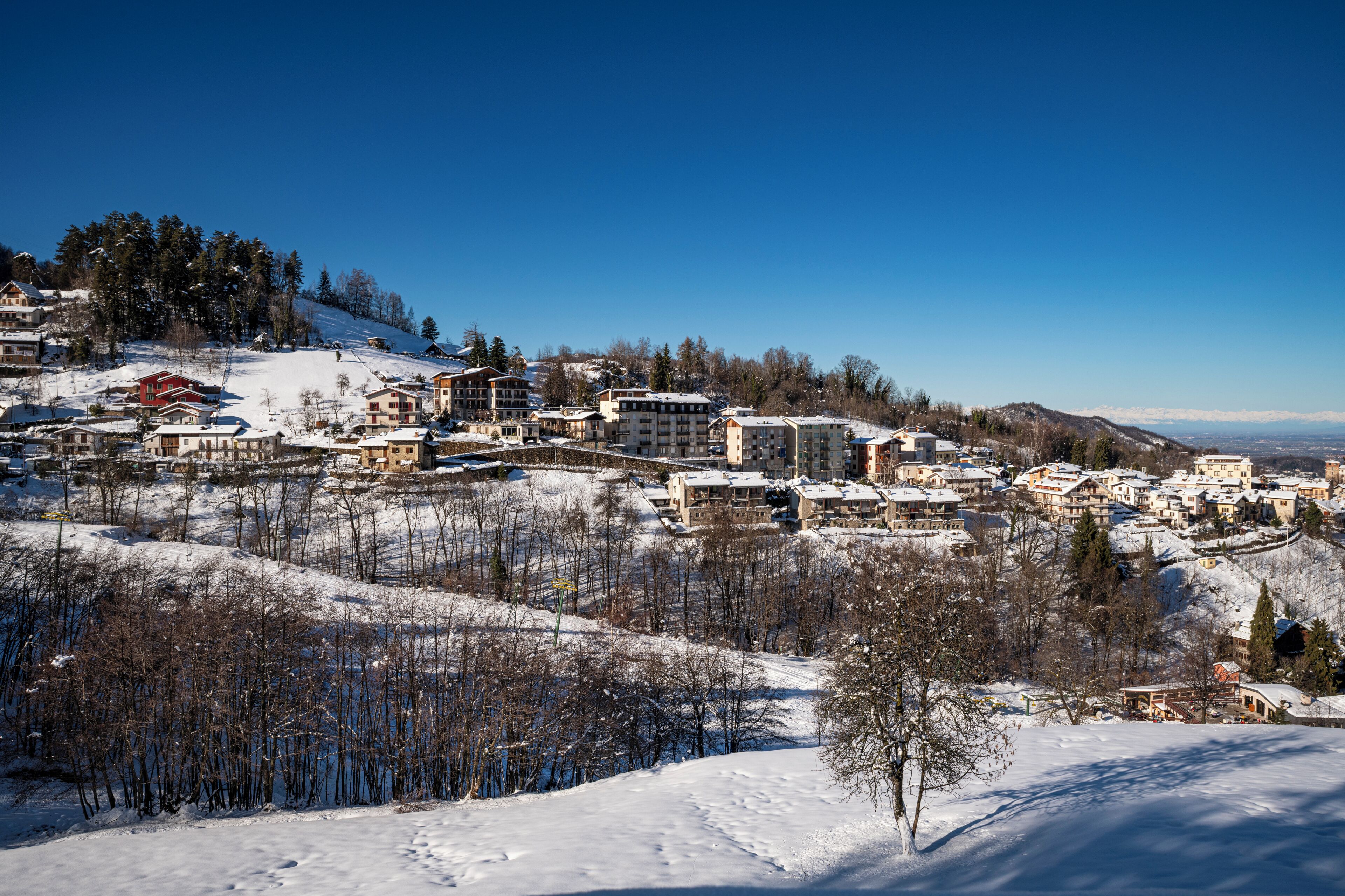 A snow-covered town with multiple buildings, including hotels and residential structures, on a hillside.