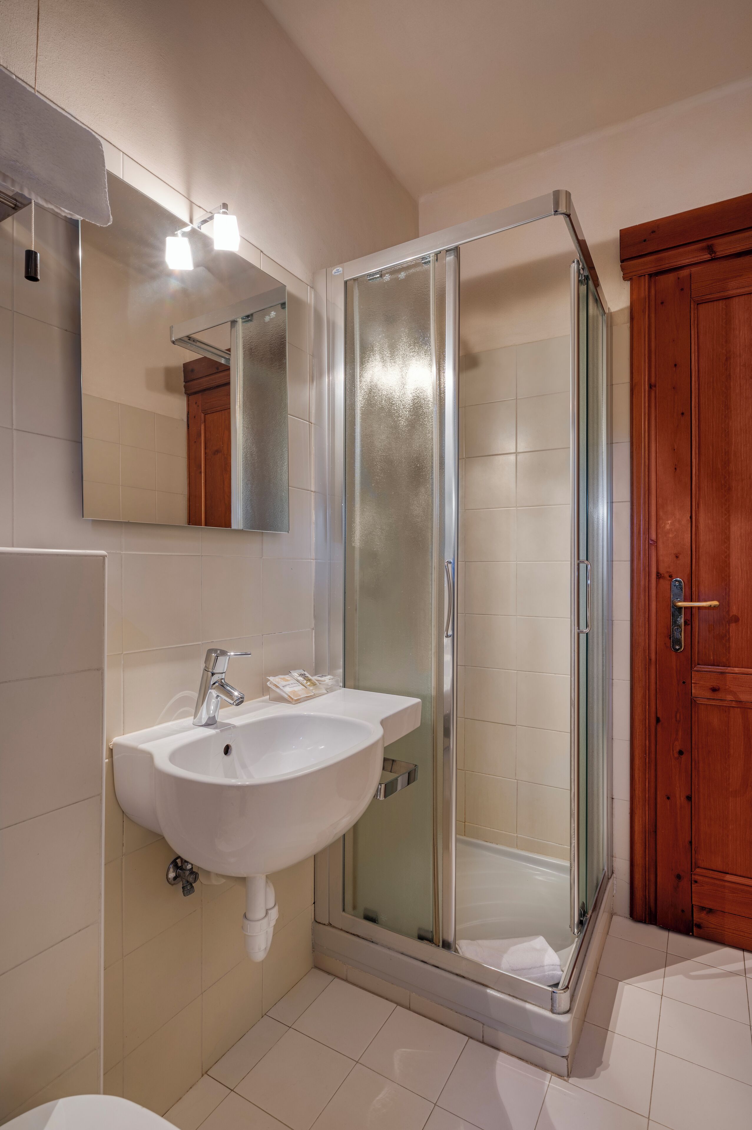 Un baño con ducha de vidrio, un lavamanos con espejo y armarios de madera.